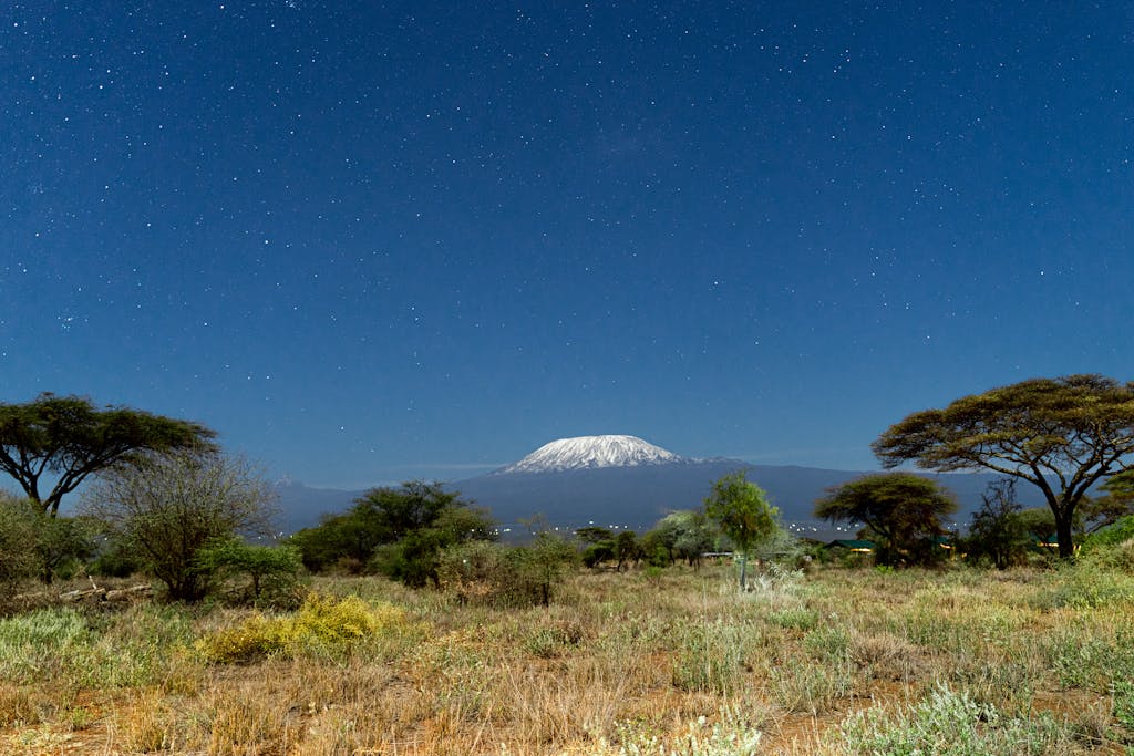 A breathtaking view of Mount Kilimanjaro framed by a clear starry night sky from Kajiado County, Kenya.