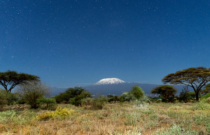 A breathtaking view of Mount Kilimanjaro framed by a clear starry night sky from Kajiado County, Kenya.