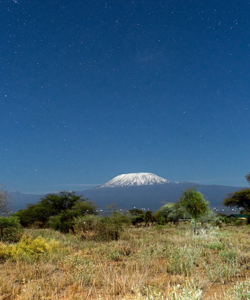 A breathtaking view of Mount Kilimanjaro framed by a clear starry night sky from Kajiado County, Kenya.