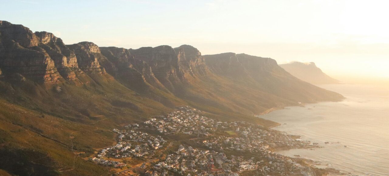 A stunning aerial view of Cape Town's coastline with mountains and sea at sunset.