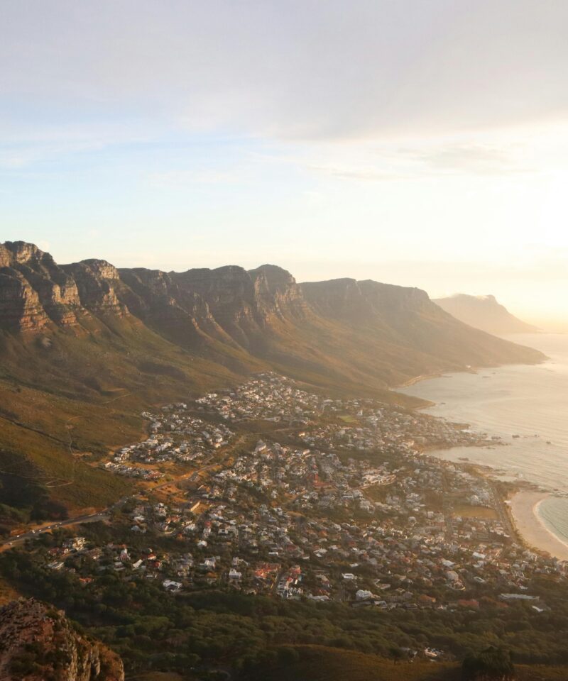 A stunning aerial view of Cape Town's coastline with mountains and sea at sunset.