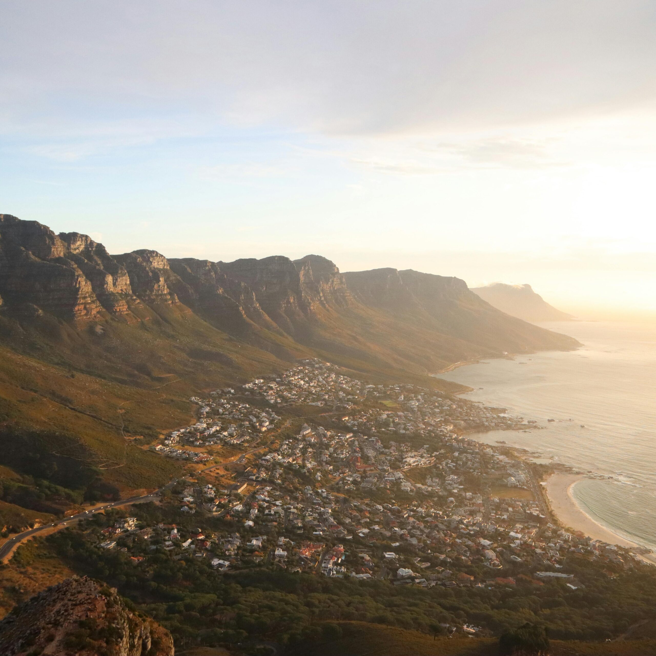 A stunning aerial view of Cape Town's coastline with mountains and sea at sunset.